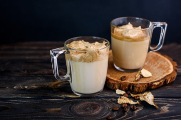 Delicious and fragrant dalgona coffee in glass cups, cinnamon sticks, dried mushrooms, a spoon of instant coffee, sugar.