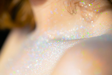 Clavicle of a girl in sparkles of colored iridescent,