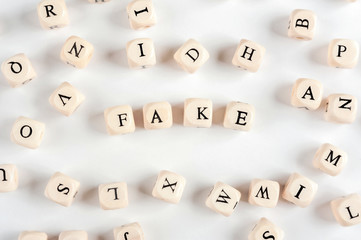 The word FAKE is made up of wooden blocks with letters. Background with letters..