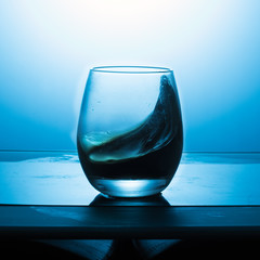 Splash of wine in a glass on a blue textured background.