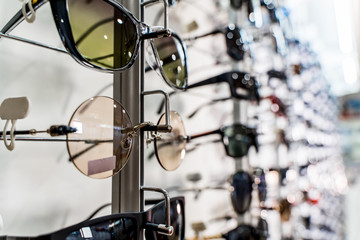 Fototapeta na wymiar Raw of fashion elegance sunglasses in the store. Showcase with sunglasses in modern ophthalmic store. Closeup.