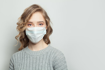Pretty woman wearing a face mask on gray background