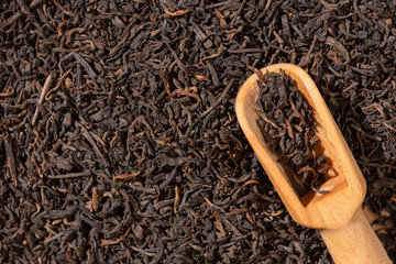 Dry Puer tea leaves and wooden spoon,close up,hard light.