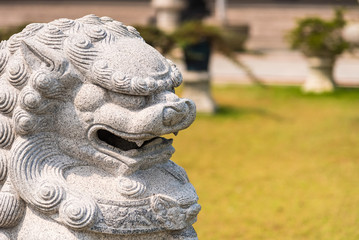 Closeup of Chinese lion sculpture in green garden.