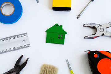 Wooden  house toy and construction tools on white background .
