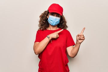 Fototapeta na wymiar Middle age delivery woman wearing red cap and coronavirus protection mask smiling and looking at the camera pointing with two hands and fingers to the side.
