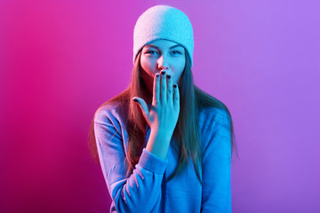 Image of attractive young lady with long beautiful hair, posing and covering her mouth with hand,...