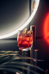 bright cocktail in a beautiful glass neon lighting and plants background 