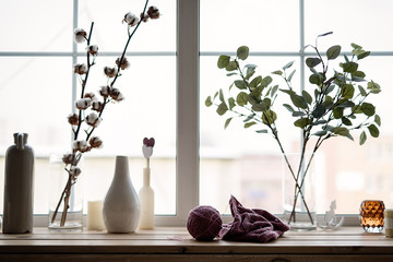 against the background of the window on the windowsill there are vases with flowers, against the...