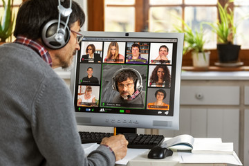 A moderator manages a video conference from his home office  - obrazy, fototapety, plakaty