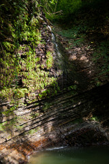 A small mountain waterfall with very clean ice water. Gorge. Rock, stone, water, ivy.