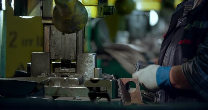 Press operation Small parts are inserted into the press. Close up of worker hands