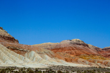 Colored, layered Aktau mountains in Kazakhstan among saxaul bushes. Above is a space for text.