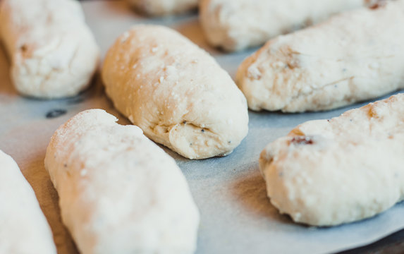 Raw curd buns with raisins lie on a baking sheet. Raw dough. Unbaked buns. Selective focus