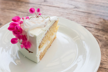 Coconut cake decorated with pink flowers on white plate