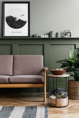 Stylish interior design of living room at cozy apartment with stylish sofa, plants, design furnitures, decoration and elegant accessories. Mock up poster frames on the shelf.  Home staging.