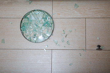 A close-up of a broken glass lid lies on a stake of tile. shards of glass shine. soft focus, top view