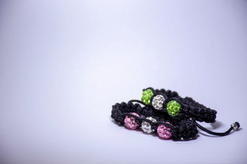 Handmade bracelets with green, pink and white beads and zircons on white background