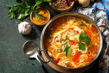 Tukpa soup Indian cuisine. Hot noodle soup with chicken ginger, cilantro and garlic in a bowl on a dark tabletop. Copy space.