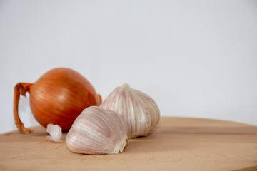 Onion and garlic on a wooden board with a white background