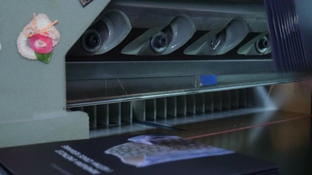 Printing house worker operating cutting machine.  Printing press, paper cutting on the cutting machine, printing production.
