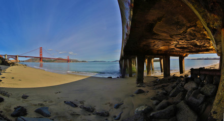 Golden Gate Bridge unique perspective from under wharf with nice sun reflection on concrete.
