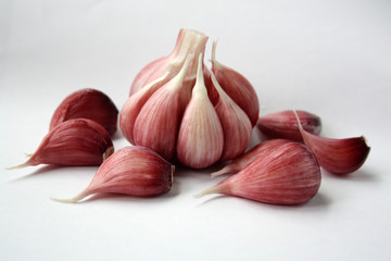 Unpeeled garlic cloves on a white surface
