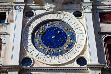 Close up. The astronomical clock of Venice ("Torre dell'Orologio") is the medieval mechanical clock tower with a blue dial, golden zodiac symbols and stars on the Piazza San Marco in Veneto, Italy.