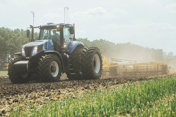 big blue tractor with big wheels in a field in summer at an agricultural exhibition