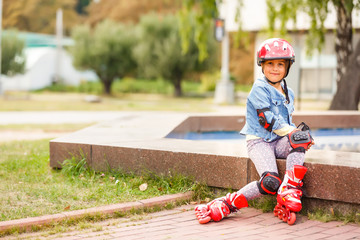 Three children sitting on a park bench after rollers