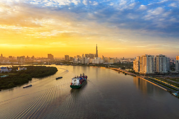 Fototapeta premium Aerial view of center Ho Chi Minh City, Vietnam with development buildings, transportation, energy power infrastructure. View from the Saigon river with ships on the river. 