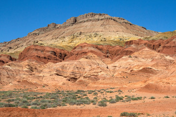 Fototapeta premium Colored, layered Aktau mountains in Kazakhstan among saxaul bushes.