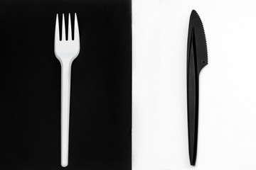 White fork and black knife. Fork on a black background, knife on a white background.