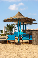 Group of straw umbrellas and deck chairs in a Red Sea sandy beach, tourist resort near Marsa Alam, Egypt, Africa 