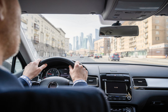 Selective focus of man hands on steering wheel driving a car on the speed highway. View from above. Moscow. Russia