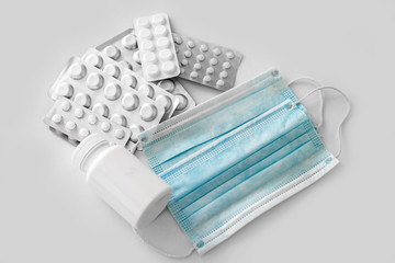Medicines: white plain breakable tablets in transparent sticks, in metal non-trasparent sticks and ampuls with anti-virus vaccine and medical anti-virus protection face mask on white background.
