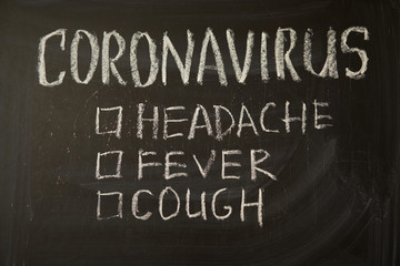 Coronavirus symptoms. Outbreak Warning. written white chalk on blackboard in connection with epidemic of coronavirus worldwide.