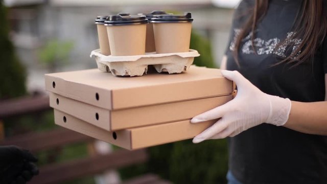 Closeup of courier give order to customer. Man from delivery service bring pizza and coffee. Hands in protective mask