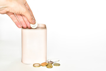 woman hand throws a coin into a beige piggy bank and money lying separately on a white background