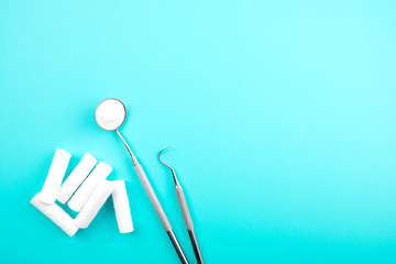 Dental instruments and tampons on blue background. Dental treatment concept. Dental mirror.