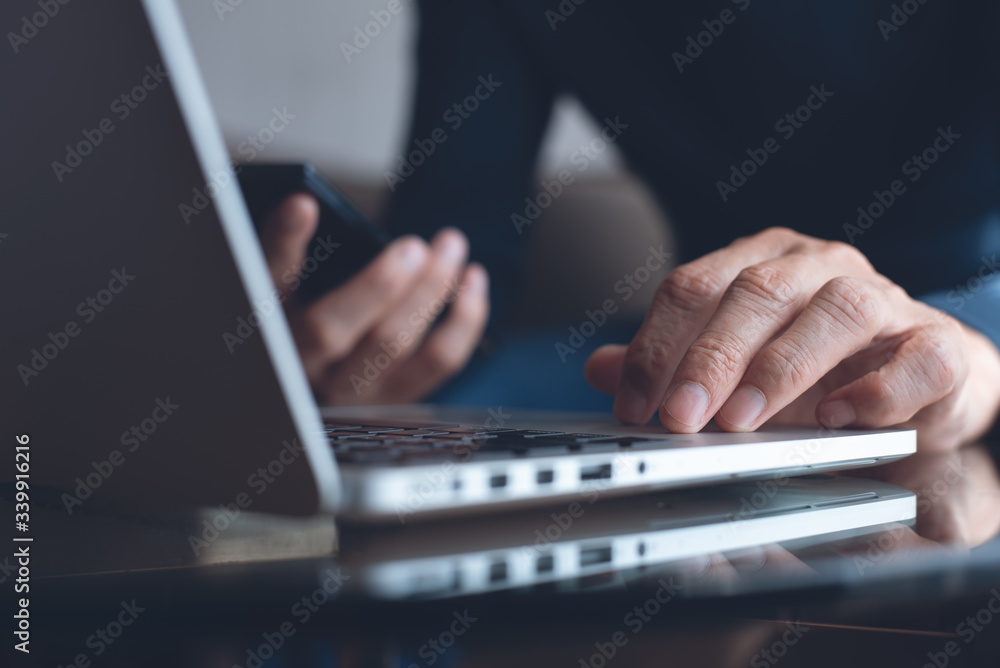 Wall mural Man using mobile phone online working on laptop