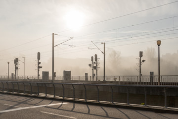 Fototapeta na wymiar Horizontal view of street and railroad tracks in a foggy morning