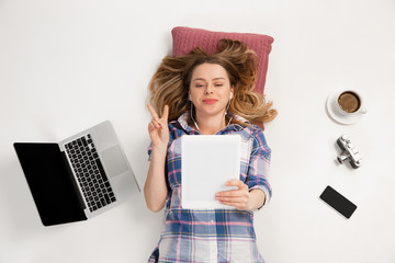 Young caucasian woman using devices, gadgets isolated on white studio background. Concept of modern...