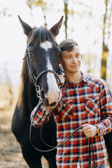 Obraz premium Portrait of young man standing by horse in countryside. 