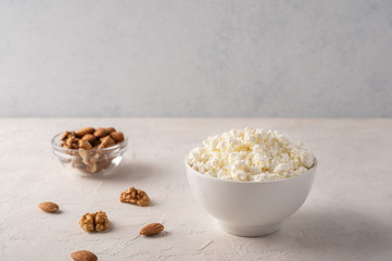 Cottage cheese in a bowl and almonds on a light background
