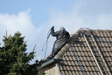 Mann bei der Reinigung eines alten Hausdaches