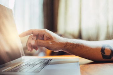 A man shopping by using laptop computer at home. Male hand typing on laptop keyboard in office. Businessman, student, work from home, distance education, online learning, studying concept