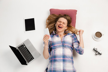 Young caucasian woman using devices, gadgets isolated on white studio background. Concept of modern...