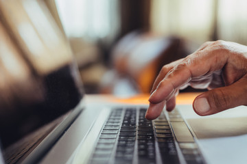 A man shopping by using laptop computer at home. Male hand typing on laptop keyboard in office. Businessman, student, work from home, distance education, online learning, studying concept