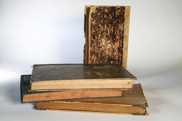 Composition of old books, with yellowed and ruined pages. Light background.